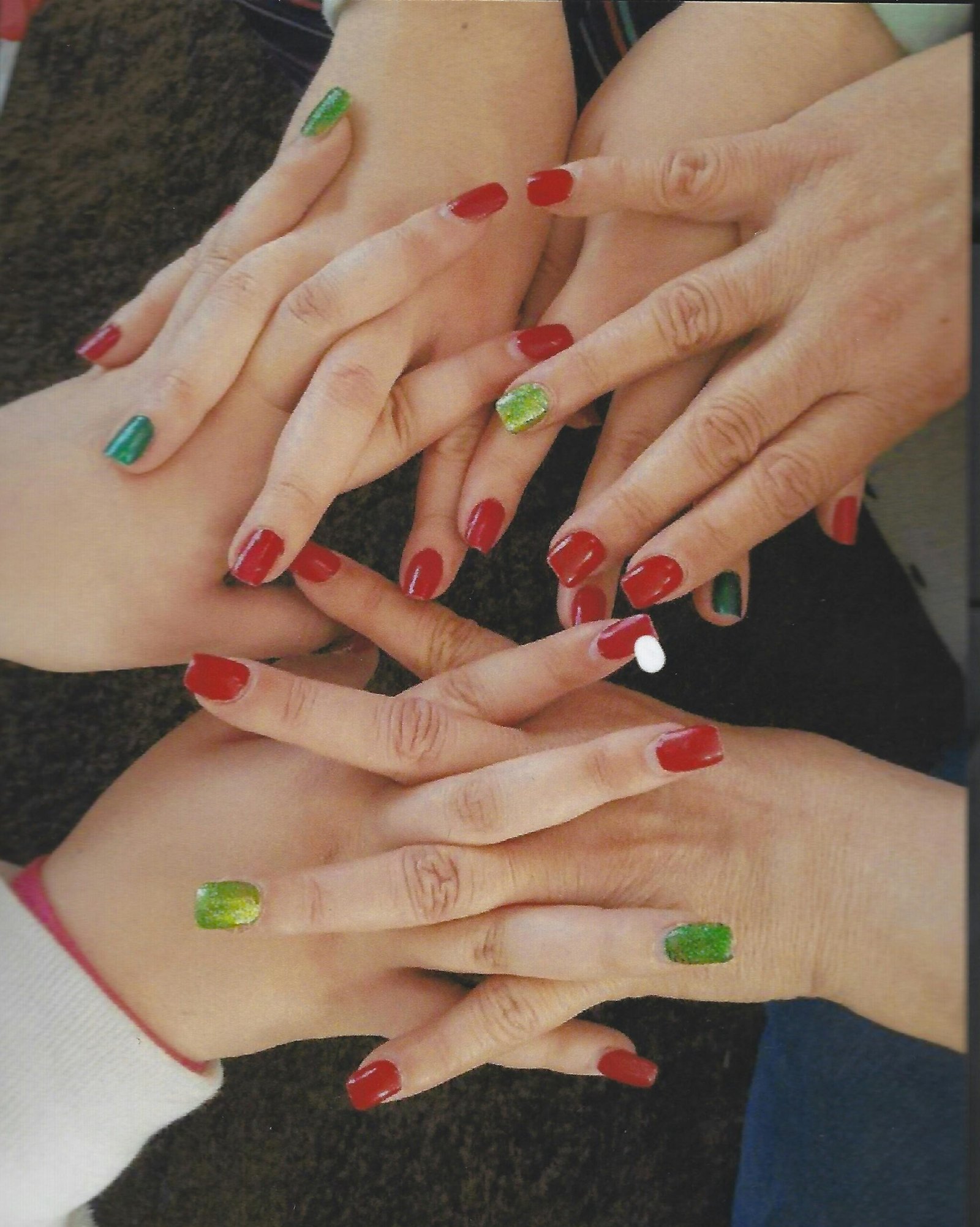 Top view of multiple hands with red and green manicured nails in a festive display.